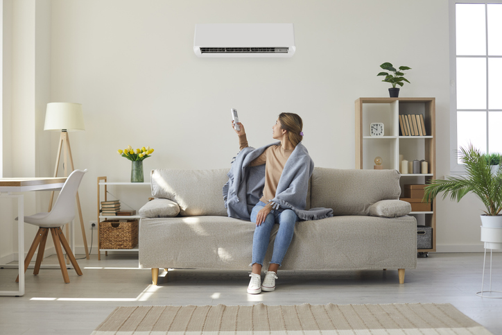 woman-enjoying-cool-fresh-air-in-her-living-room-with-air-conditioner-on-the-wall